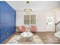 Living room with blue accent wall, pink chairs, and a statement chandelier at 1628 Savory Ln, Charlotte, NC 28216
