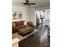 Open living room showcasing dark hardwood floors, a brown leather sofa, and an open concept kitchen at 2436 Mariners Cove Ln # 67, Denver, NC 28037