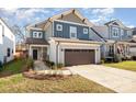 Two-story craftsman home with gray and blue siding, brown garage door, and landscaped lawn at 643 Tennyson Dr, Charlotte, NC 28208