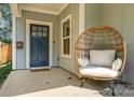 Charming front porch with navy blue door and a wicker egg chair at 643 Tennyson Dr, Charlotte, NC 28208