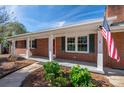 Brick ranch house with covered porch, red door, and American flag at 3026 Hazel Dr, Shelby, NC 28152