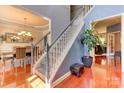 Elegant staircase with a light gray railing, hardwood floors, and chandelier at 3848 Burnage Hall Rd, Harrisburg, NC 28075