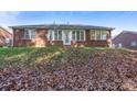 Back of house, brick, sunroom, and leaf covered yard at 103 Prestwick Ct, Salisbury, NC 28146