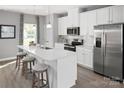 White kitchen with an island, stainless steel appliances, and white quartz countertops at 7329 Braswell Sw Dr, Concord, NC 28025