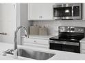 Close-up of a kitchen sink and stove with stainless steel appliances at 7329 Braswell Sw Dr, Concord, NC 28025