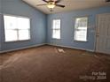 Spacious living room with light blue walls, brown carpet, and ample natural light at 7374 Sun Dance Dr, Fort Mill, SC 29707