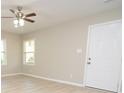 Living room with light walls, ceiling fan, hardwood floors, and white door at 403 N Ransom St, Gastonia, NC 28052