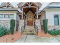 Stone and wood entryway with double doors and a covered porch at 7978 Silver Jade Dr, Denver, NC 28037