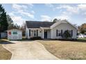 Tan house with gray door, small yard, shed, and driveway at 618 White Oak Ln, Matthews, NC 28104