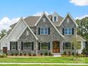 Two-story house with stone accents and a three-car garage at Lot 47 Watercourse Way # Devonshire, Belmont, NC 28012