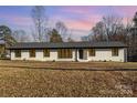 Ranch style home with white brick exterior, dark windows, and a gray roof at 3700 Pinecrest Dr, Gastonia, NC 28056