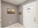 Bright entryway with gray walls, tiled floor, and a coat rack at 2562 Willow Pond Se Ln, Concord, NC 28025