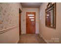 Entryway with floral wallpaper, wood-paneled door, and a mirror at 608 Hanover Dr, Shelby, NC 28150