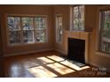 Fireplace with white mantel and granite hearth in a sunlit room with hardwood floors at 809 Pine Forest Rd, Charlotte, NC 28214