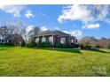 Side view of brick ranch home with landscaped yard at 8420 Locksley Dr, Harrisburg, NC 28075