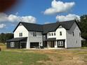 A two-story farmhouse with a black and white exterior, attached garage, and a large yard at 3907 Lawyers Rd, Monroe, NC 28110