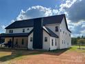 White two story farmhouse with a black roof and chimney. Features a covered porch at 3907 Lawyers Rd, Monroe, NC 28110