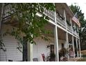 Charming two-story home with wrap-around porch, American flag, and lush greenery at 306 Mcadenville Rd, Lowell, NC 28098