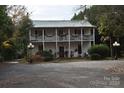 Two-story white house with wrap-around porch and mature landscaping at 306 Mcadenville Rd, Lowell, NC 28098