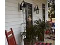 Front porch with red rocking chairs, potted plants, and elegant light fixtures at 306 Mcadenville Rd, Lowell, NC 28098