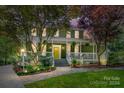 Evening view of a charming house with a white porch and well-lit landscaping at 208 Grey Rd, Davidson, NC 28036