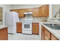 Galley kitchen, featuring wood cabinets, white appliances, and tile flooring at 16316 Redstone Mountain Ln, Charlotte, NC 28277