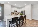 Modern kitchen with white cabinets, island with seating, and hardwood floors at 3732 Inkberry Dr, Gastonia, NC 28056