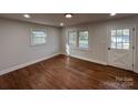 Living room with hardwood floors, multiple windows, and a white door at 1327 Marble St, Charlotte, NC 28208