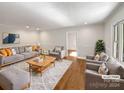 Virtually staged living room with hardwood floors, gray sofa and armchairs at 104 Abingdon Cir, Huntersville, NC 28078