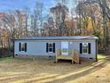 Gray mobile home with black shutters and a wood deck, sitting on a grassy lot at 46 Kidd And Brown Rd, Hiddenite, NC 28636