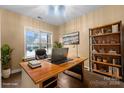 Virtually staged home office with a large wooden desk, bookshelf, and comfortable chair at 3045 Bronwood Pl, Lancaster, SC 29720