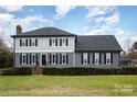 Gray sided two-story house with shutters and a manicured lawn at 8823 Dartmoor Pl, Mint Hill, NC 28227