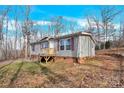 Gray mobile home with brick base and wooden deck, angled view showing landscaping at 633 Lhasa Apso Ln, Iron Station, NC 28080