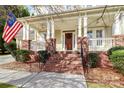 Inviting front porch with brick columns, American flag and a cozy swing at 8002 Morehouse Dr, Waxhaw, NC 28173