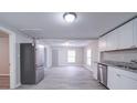 Modern kitchen with white cabinets, granite counters, stainless steel appliances, and gray wood-look floors at 208 Oakland Dr, Lowell, NC 28098