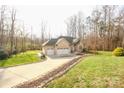 A brick ranch home with a three-car garage and large driveway, nestled among trees at 152 Stacybrook Se Dr, Concord, NC 28025