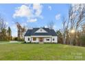 Beautiful white farmhouse with a lush green lawn and surrounding trees at 6425 Private Dr, Mount Pleasant, NC 28124