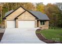 Front exterior of a brick home with a three-car garage and a fire pit at 4531 Deer Run Rd, Rock Hill, SC 29732