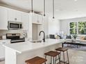 Open concept kitchen features white cabinets, island with seating, and stainless steel appliances at 7022 Impulse Ct, Charlotte, NC 28205
