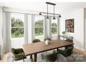 Bright dining room with wood table and green velvet chairs, offering natural light at 8008 Cedarsmith Ct, Charlotte, NC 28217