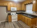 Kitchen with wood cabinets, white appliances, and dark countertops at 625 Kilborne Dr, Gastonia, NC 28052