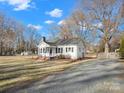 White house with gravel driveway and a large yard, showcasing a shed at 8532 Old Plank Rd, Charlotte, NC 28216