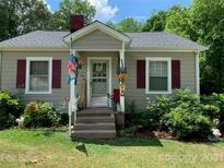 Cozy cottage with gray siding, red shutters, and a welcoming front porch at 507 North Dr, Cherryville, NC 28021