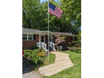 Brick ranch home with landscaped yard, walkway, and American flag at 406 Ohio Ave, Bessemer City, NC 28016