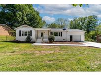 White ranch house with black shutters, attached garage, and landscaped lawn at 506 E Maine Ave, Bessemer City, NC 28016