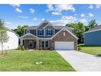 Two story house with stone and gray siding, white garage door, and manicured lawn at 224 Winford Dr, Troutman, NC 28116