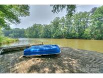 Wooden dock on lake with blue rowboat; lush trees surround at 4115 Cascade St, Terrell, NC 28682