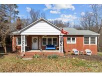 Brick ranch house with a covered porch, welcoming front yard, and mature trees at 8300 Mount Holly Rd, Charlotte, NC 28214