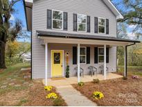 Two-story house with gray siding, black shutters, and a yellow front door at 310 New Bern Ave, Statesville, NC 28677