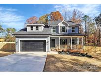 Two-story house with gray siding, black garage door, and a small front porch at 1975 Ripplerock Rd, Fort Mill, SC 29715